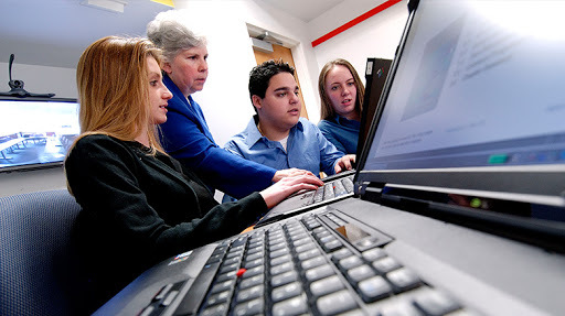 Students and a faculty member typing at computers.
